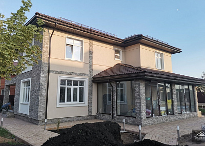 Наружная отделка дома выполнена из декоративной штукатурки и искусственного камня.